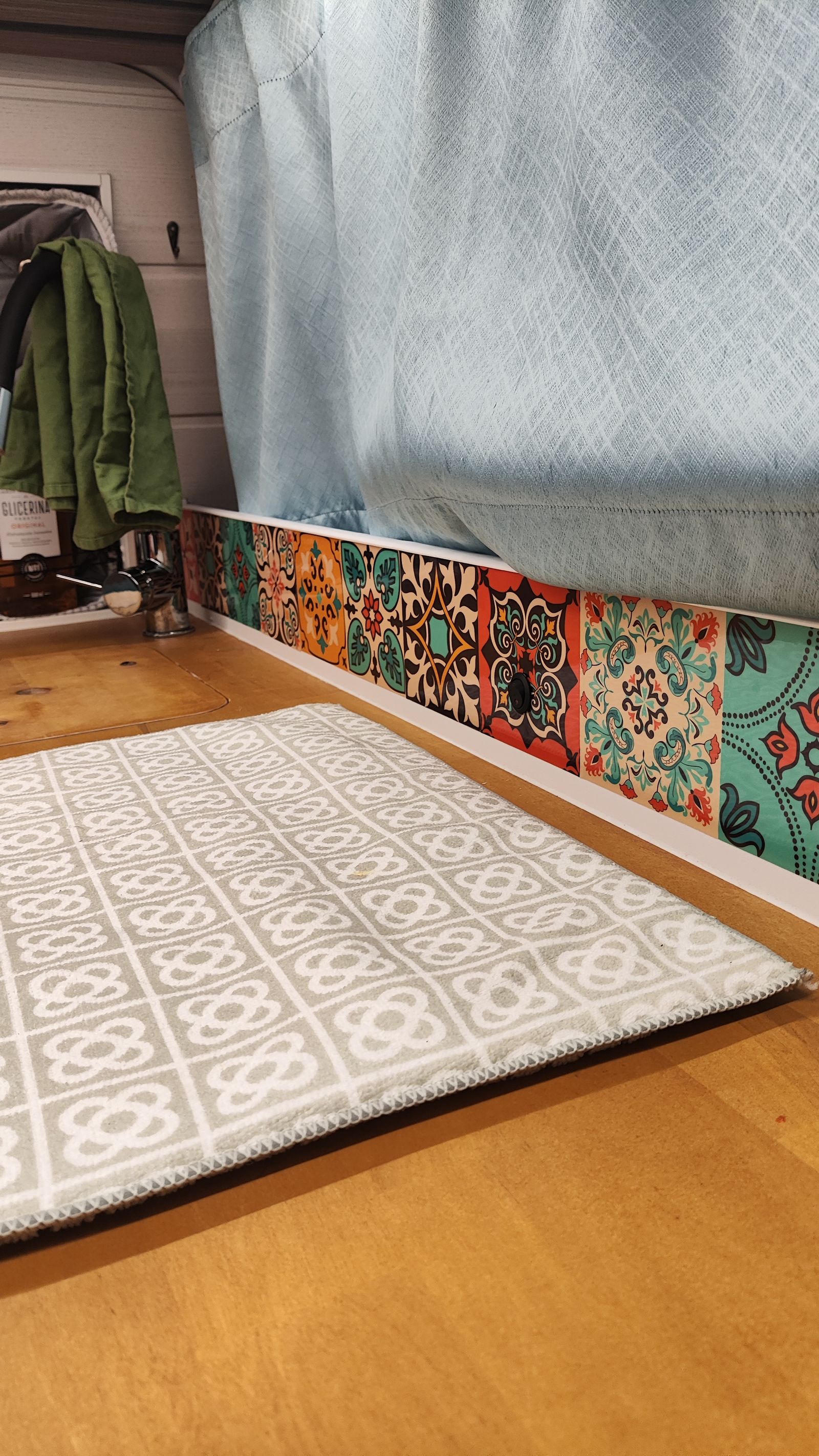 Detalle del suelo de madera con la alfombra y los azulejos hidráulicos de la cocina.