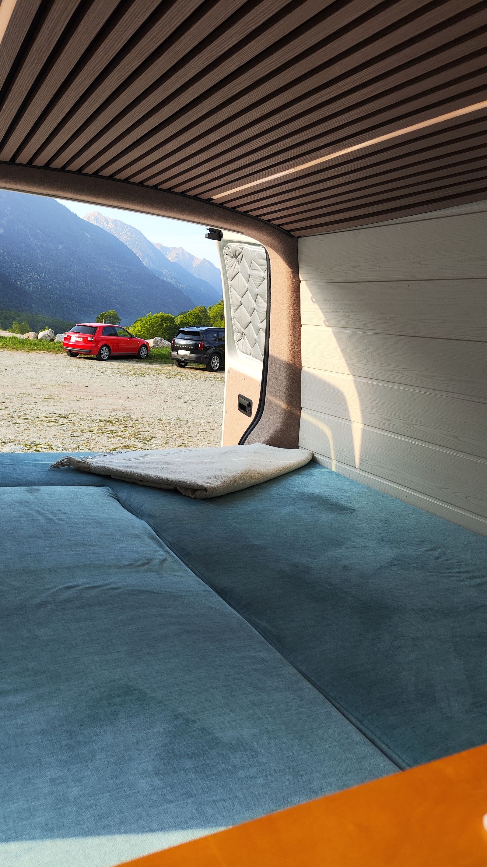 Desde dentro: la cama montada y el portón abierto a un valle de montaña.