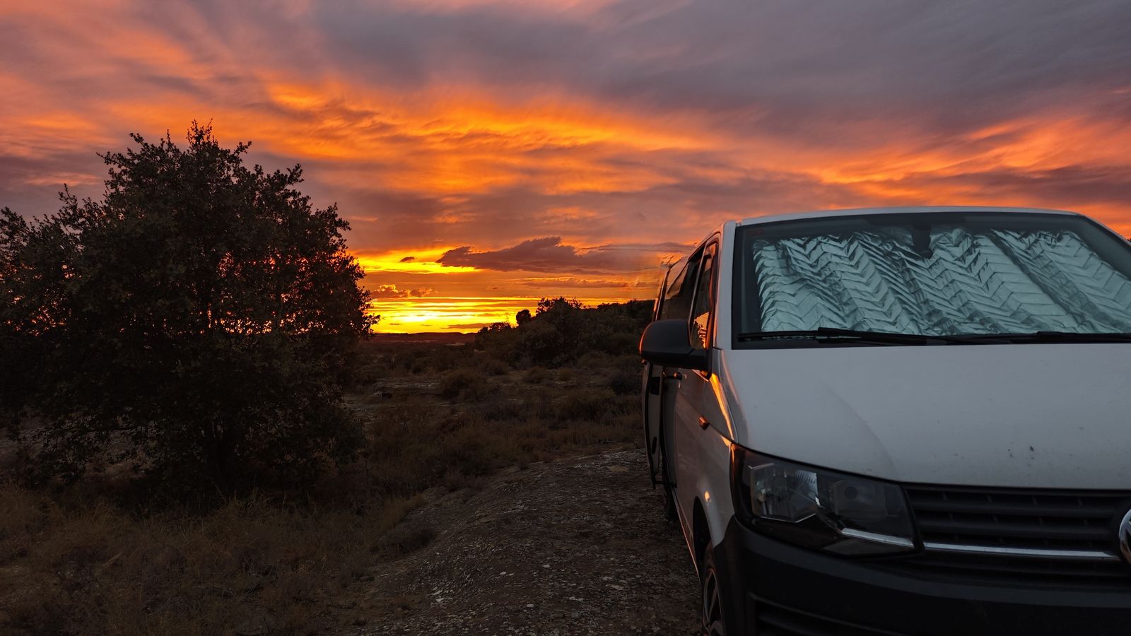 La MakakoVan aparcada en un altiplano al atardecer, con el cielo encendido en naranja sobre el horizonte.