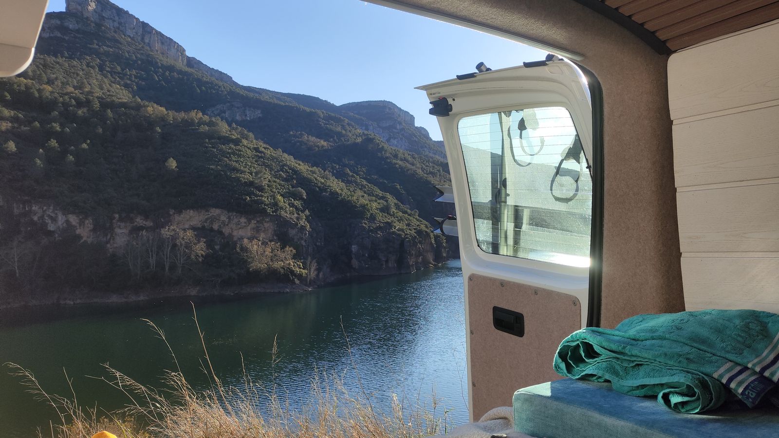 La puerta lateral abierta enmarca un embalse encajado entre paredes de roca.