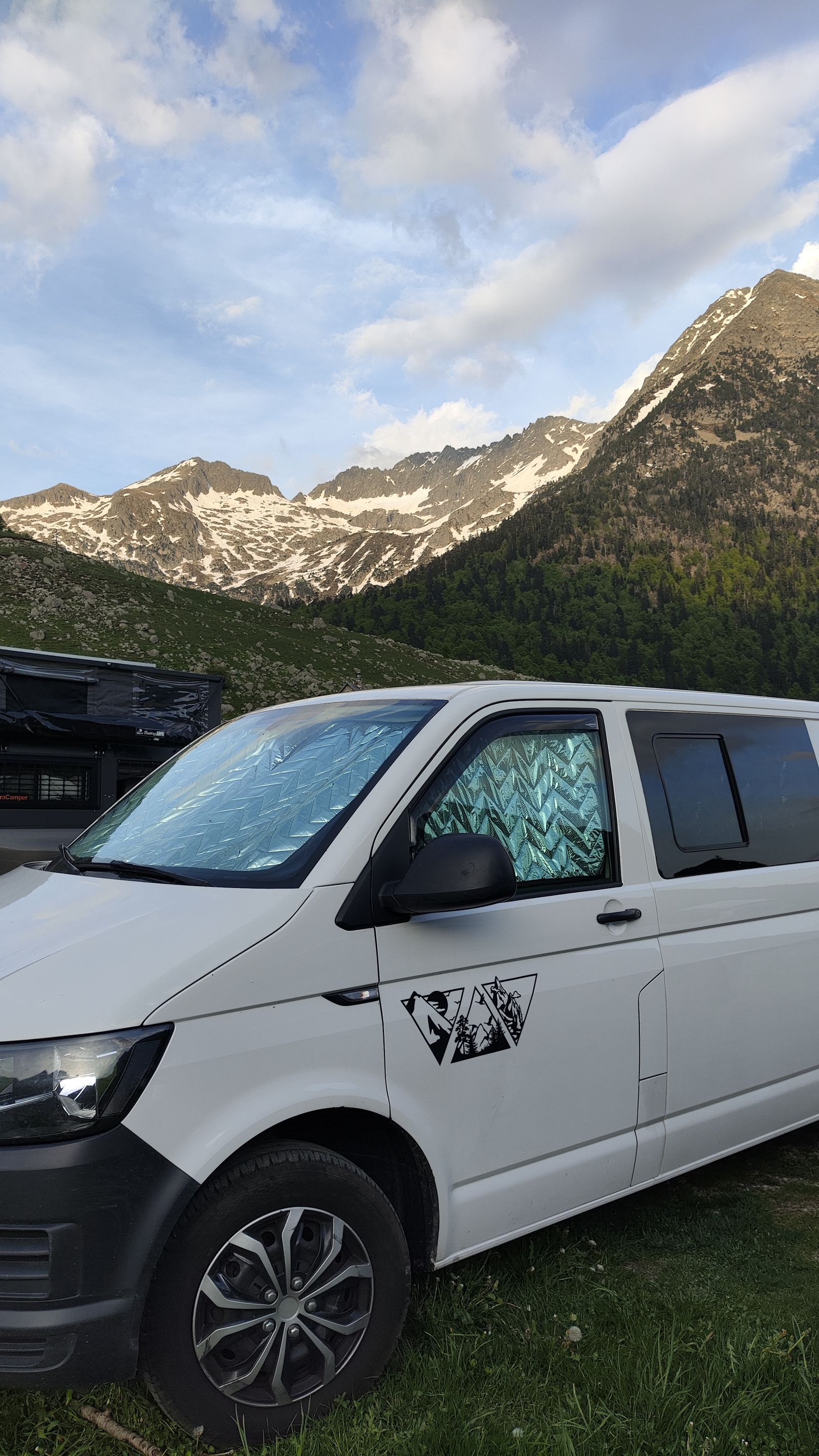 La furgo aparcada en un valle alpino con las cumbres nevadas detrás.